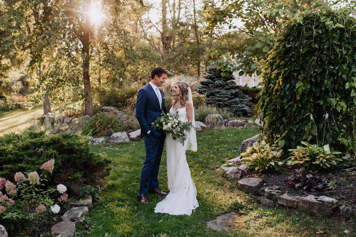 Bride and groom standing in garden at sunset