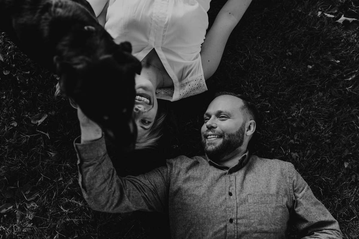 Couple laying on ground with dog during their engagement photo shoot at Ottawa's Arboretum