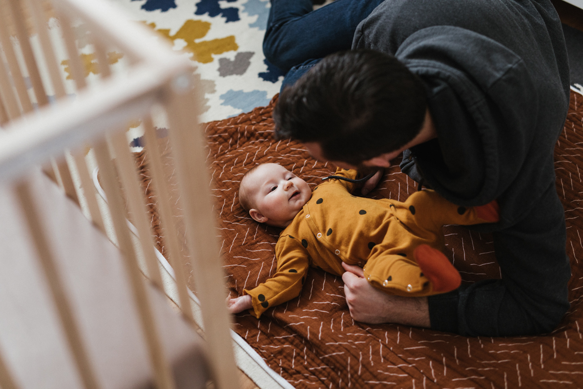 Baby laying on floor with father
