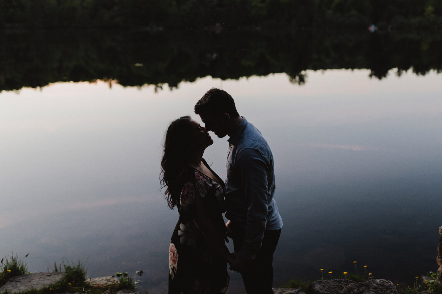 Silhoutte of couple standing in front of lake during their engagement shoot